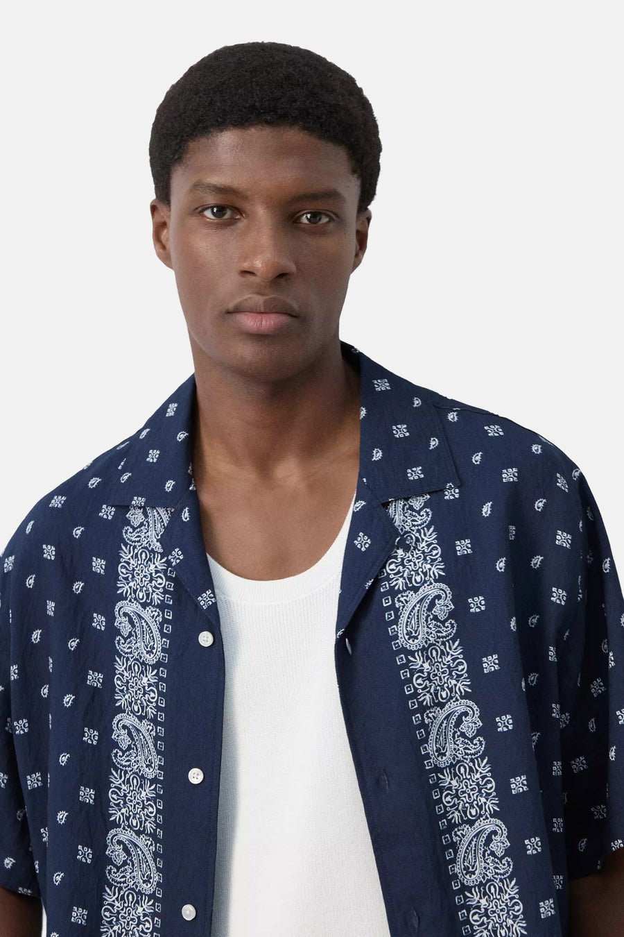 Blauw hemd met korte mouwen van MANGO, met witte paisley en geometrische patronen, gedragen over een wit onderhemd.