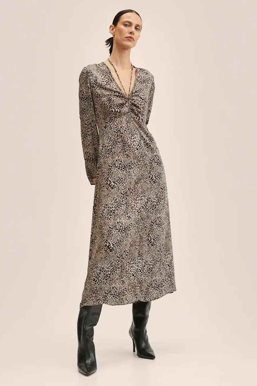 Robe beige de MANGO, avec imprimé léopard et longues manches, portée avec des bottes noires.