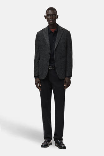 Multikleurige blazer van MANGO, gedragen met een zwart poloshirt, zwarte pantalon en zwarte loafers.
