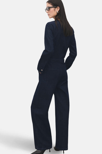 Donkerblauwe denim jumpsuit van MANGO, met lange mouwen, wijde pijpen en gedragen met een zonnebril.
