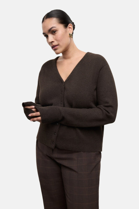 Vrouw met bruine cardigan en geruite broek.