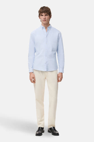 Blauw overhemd met lange mouwen van MANGO, met een knoopsluiting en gedragen met een beige broek en zwarte schoenen.
