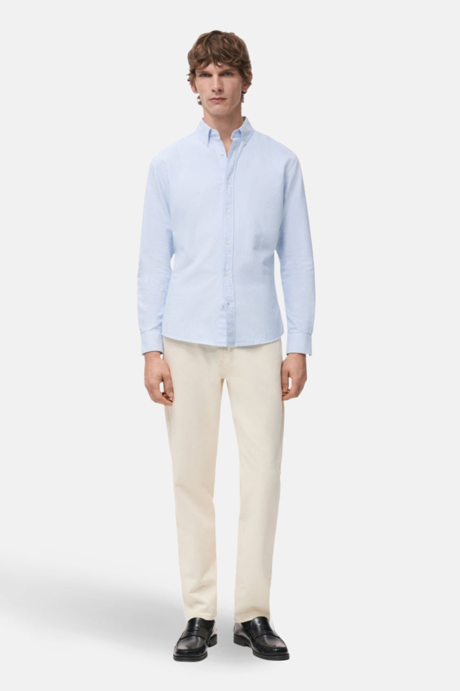 Blauw overhemd met lange mouwen van MANGO, met een knoopsluiting en gedragen met een beige broek en zwarte schoenen.
