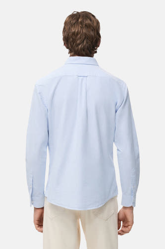 Blauw gestreept overhemd met lange mouwen van MANGO, gezien vanaf de achterkant, gedragen met een crèmekleurige broek.
