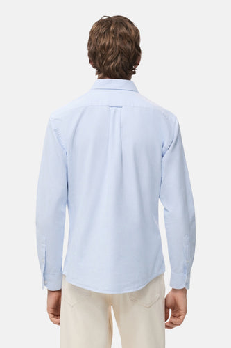 Blauw gestreept overhemd met lange mouwen van MANGO, gezien vanaf de achterkant, gedragen met een crèmekleurige broek.
