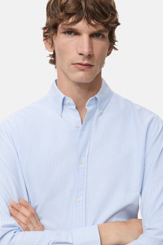 Blauw gestreept overhemd met lange mouwen van MANGO, met een button-down kraag en gekruiste armen.
