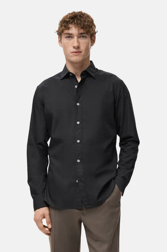 Chemise noire à manches longues de MANGO, vue de derrière, avec un pantalon marron.