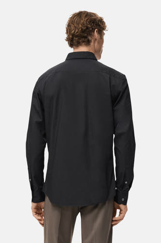 Zwart overhemd met lange mouwen van MANGO, gezien van achteren, met bruine pantalon.
