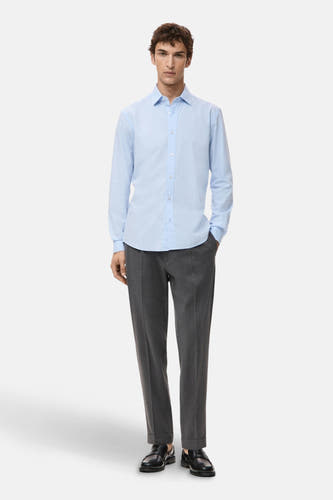 Chemise bleue à manches longues de MANGO, associée à des pantalons gris et des chaussures noires.