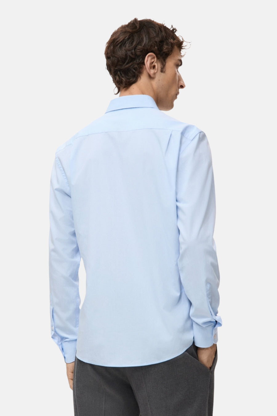 Chemise bleue à manches longues de MANGO, vue de derrière avec un pantalon gris.