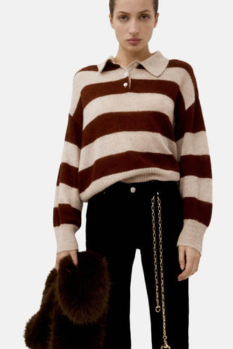 Pull marron de MANGO avec des rayures beige, porté avec un pantalon noir et un manteau de fourrure marron vu de l'arrière.