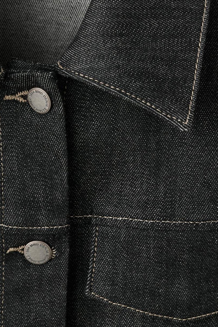 Denim jeansjas van MANGO, met knopen en contrasterende stiksels, detailopname.
