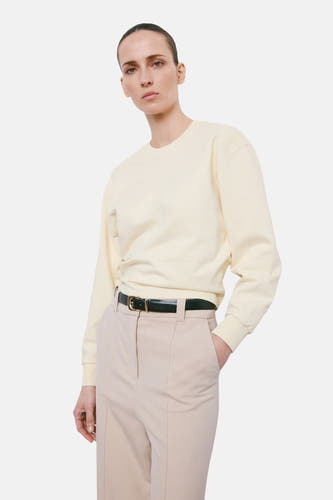 Beige sweater van MANGO, met lange mouwen en gedragen met een zwarte riem en beige pantalon.
