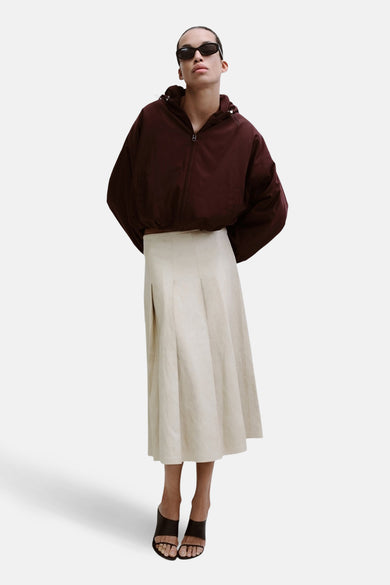 Jupe longue beige de MANGO, avec des plis et une texture légère, combinée à une veste bordeaux à capuche.