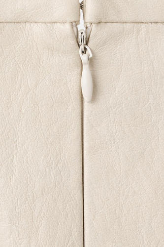 Lange beige rok van MANGO, met een gladde textuur en een witte ritssluiting in het midden.

