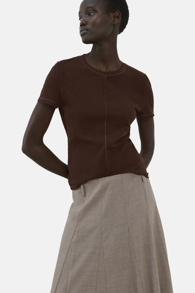 T-shirt à manches courtes marron de MANGO, combiné avec une longue jupe grise coupe trapèze et des talons noirs, vu de dos.