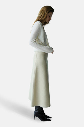 Ecru gilet van MANGO, gedragen met een witte trui en beige rok, in zijaanzicht.
