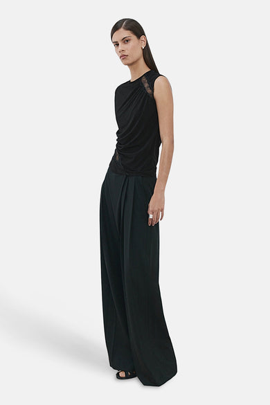 Chemisier noir sans manches de MANGO, avec détails en dentelle sur l'épaule et drapé sur le côté.