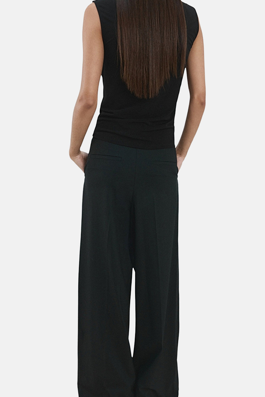 Zwarte mouwloze blouse van MANGO, met rechte pasvorm en lange bruine haren op de rug.