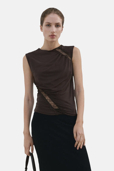 Chemisier marron sans manches de MANGO, avec une jupe noire et des bottes noires en cuir à talons.