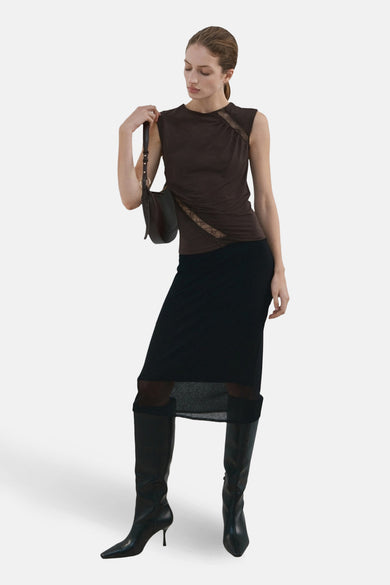 Chemisier marron sans manches de MANGO, avec détails en dentelle et porté avec une jupe noire et des bottes.
