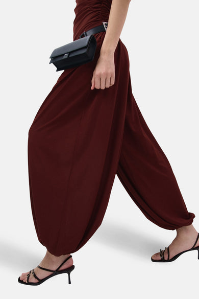 Bruine broek van MANGO, met wijde pijpen en een elastische tailleband, gecombineerd met een zwarte riem en sandalen met hak.