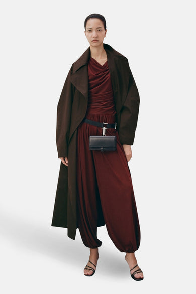 Bruine broek van MANGO, met wijde pijpen en gecombineerd met een lange jas en riem met tasje.
