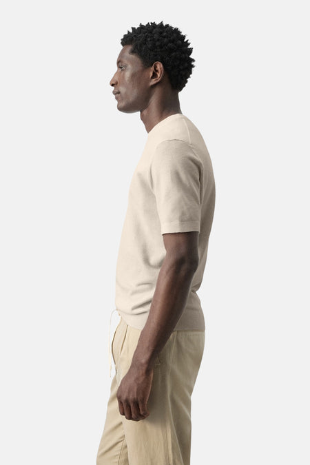 T-shirt beige à manches courtes de MANGO, vue de côté, porté avec un pantalon kaki à cordon de serrage.