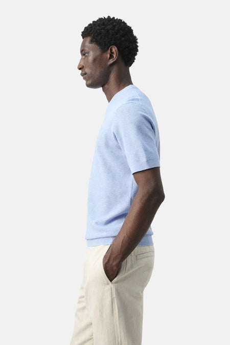 T-shirt bleu à manches courtes de MANGO, vu de profil, porté avec un pantalon beige.