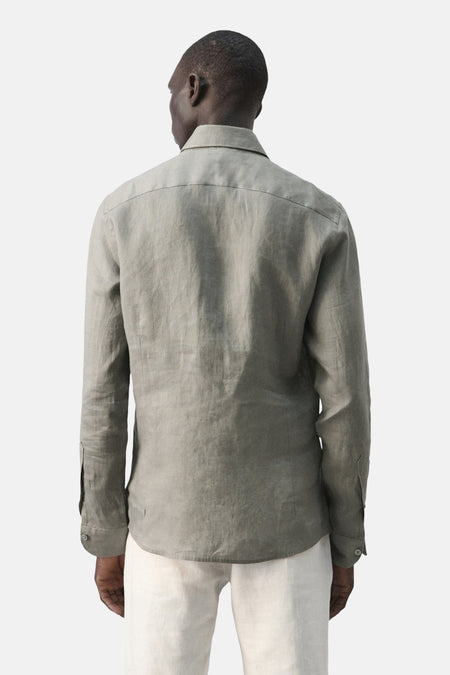 Bruin herenoverhemd met lange mouwen van MANGO, achterkant getoond, gedragen met een crèmekleurige broek.