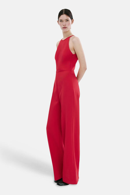 Rode jumpsuit van MANGO, met wijde pijpen en een aansluitende top, in profiel gezien.
