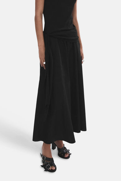 Zwarte lange rok van MANGO met knoopdetail in de taille, gedragen met zwarte muiltjes.