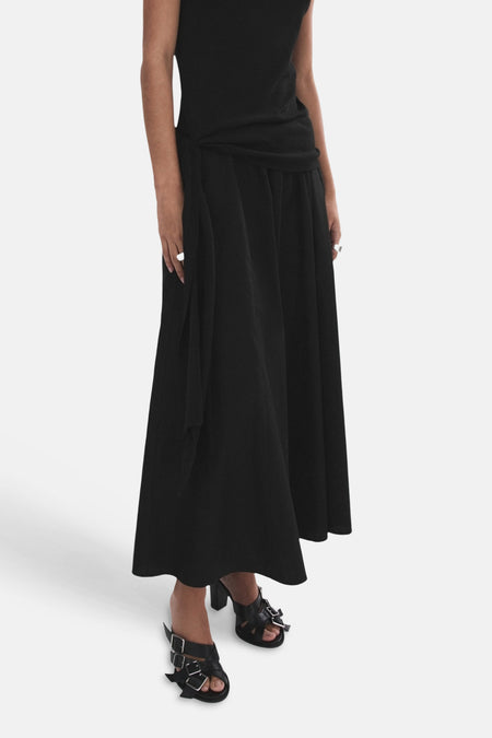 Zwarte lange rok van MANGO met knoopdetail in de taille, gedragen met zwarte muiltjes.