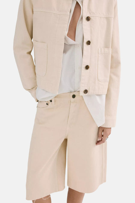 Lichtgele bermuda van MANGO, gecombineerd met een wit overhemd en crèmekleurig cropped jack met bruine knopen.