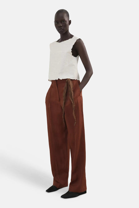 Wit T-shirt van MANGO met geschulpte randen, gedragen door een model met bruine broek.