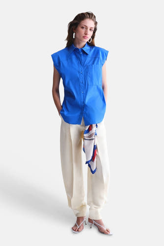 Blauw mouwloos hemd van MANGO met kraag en zakken, gecombineerd met crèmekleurige broek.