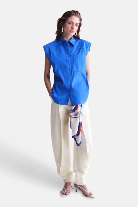 Blauw mouwloos hemd van MANGO met kraag en zakken, gecombineerd met crèmekleurige broek.