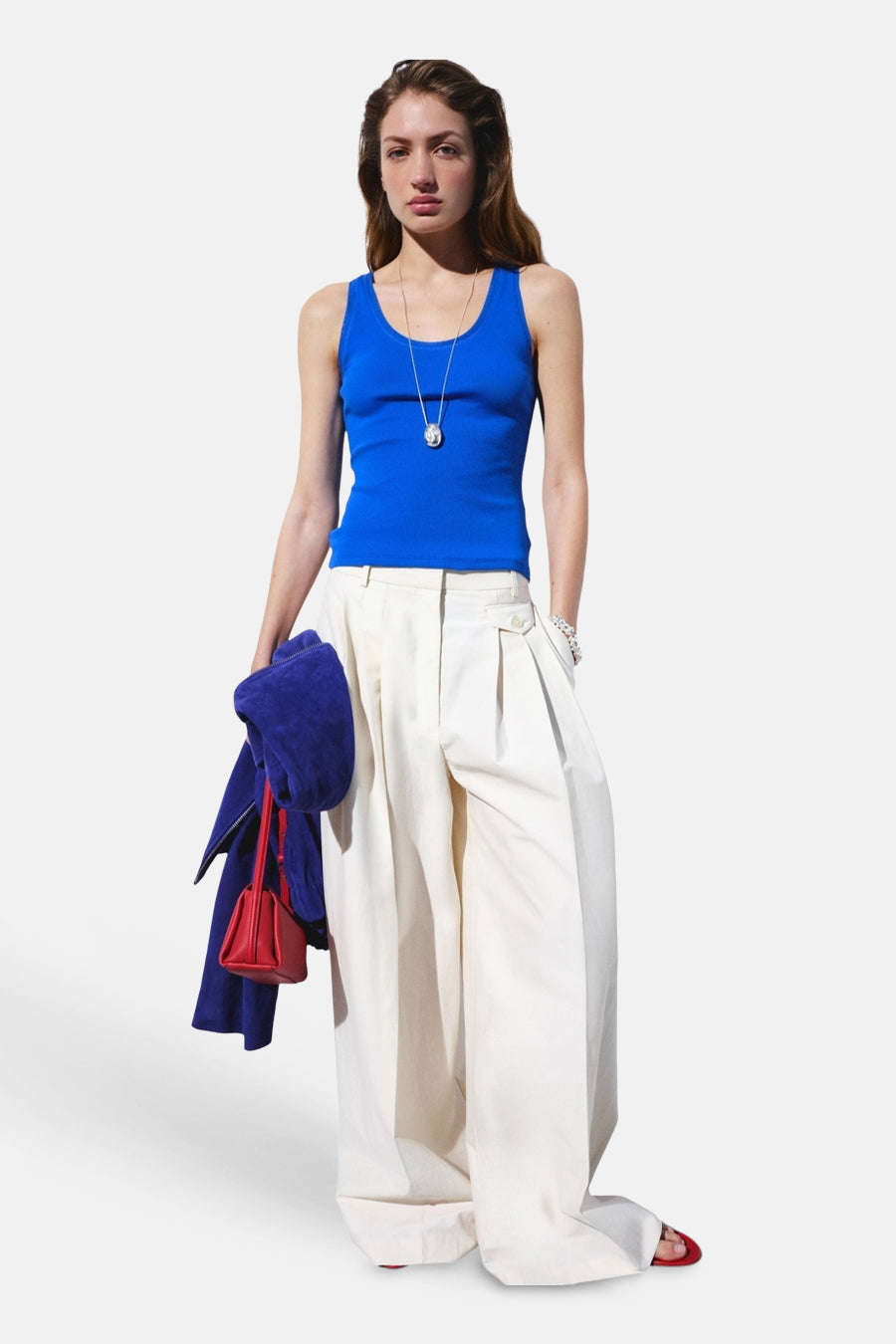 Blauwe geribbelde tanktop van MANGO, gedragen met witte wijde broek, zilveren ketting, rode handtas en blauwe jas.