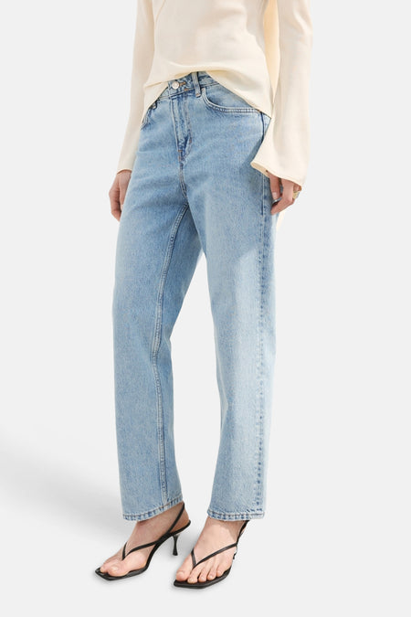 Jeans straight van lichtblauwe denim van MANGO, gecombineerd met een crèmekleurige top en zwarte sandalen met hak.
