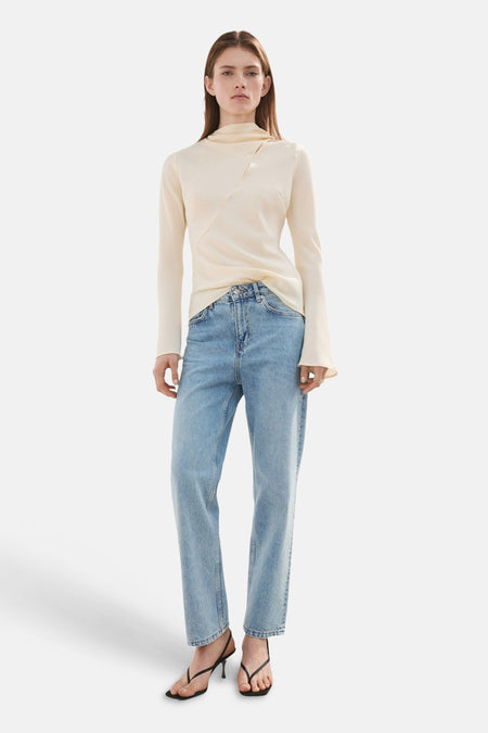 Straight jeans in lichtblauw denim van MANGO, gecombineerd met een ecru top en zwarte hakken.