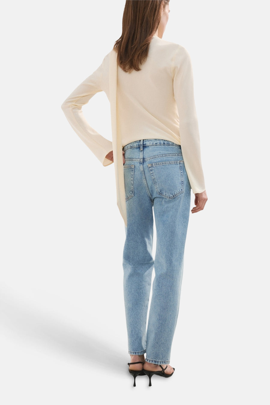 Jeans straight van lichtblauw denim van MANGO, gezien van achteren met een top en sandalen.

