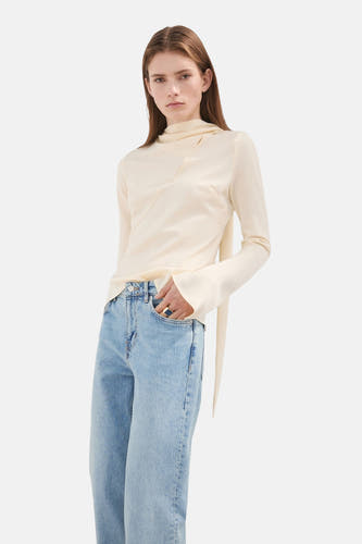 Jeans straight van MANGO van lichtblauwe denim, gedragen met een crèmekleurige top met lange mouwen en een opvallende ring.
