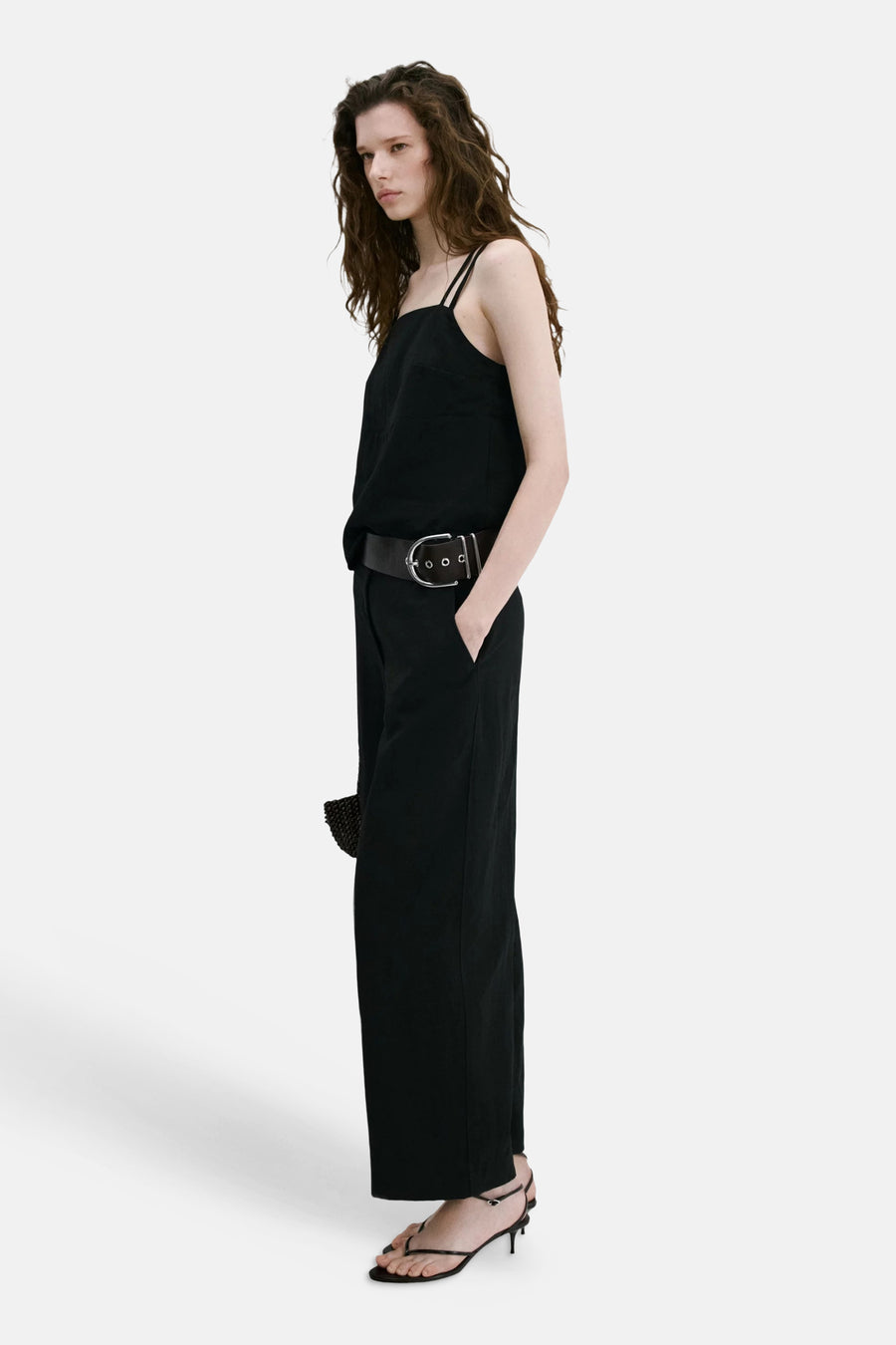Zwarte broek van MANGO met wijde pijpen, van opzij gezien op een model met een zwarte top en brede riem.