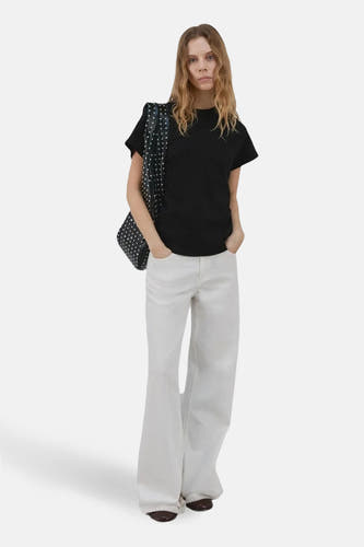 Zwarte top van MANGO, met korte mouwen en gedragen met witte broek en een tas met stippen.
