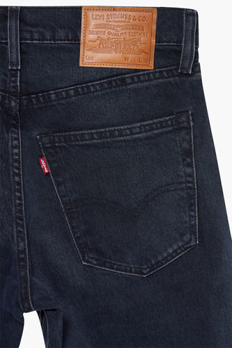 Donkerblauwe tapered jeans van Levi's®, met rode tab en bruin leren label aan de achterkant.
