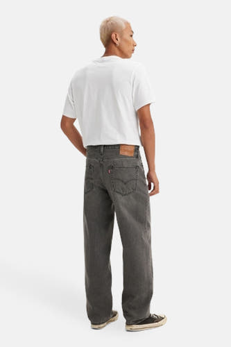 Jean droit en denim gris foncé de Levi's®, vu de derrière, avec un étiquette en cuir brun et des chaussures noires.