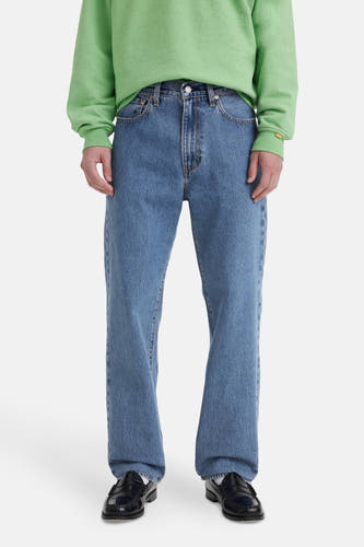 Jeans straight mid blue denim van Levi's®, gedragen met een groene trui en zwarte loafers.
