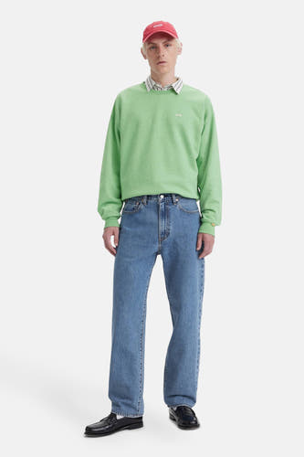 Rechte blauwe denim jeans van Levi's, gedragen met een groene sweater en zwarte loafers.