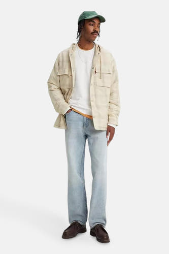 Jean bleu clair droit de Levi's, associé à un t-shirt blanc, une chemise beige et des chaussures marron.