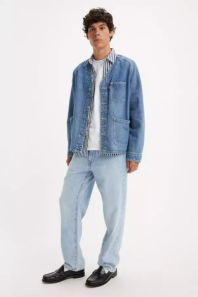 Lichtblauwe straight jeans van Levi's, gecombineerd met een wit T-shirt en een blauw gestreept overhemd.